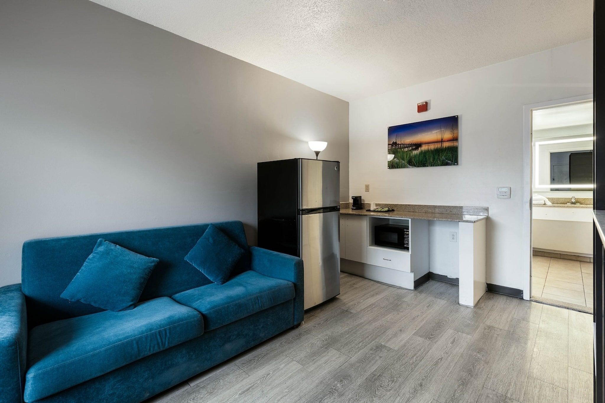 Um espaço compacto com cozinha compacta, um sofá azul e um quadro na parede.