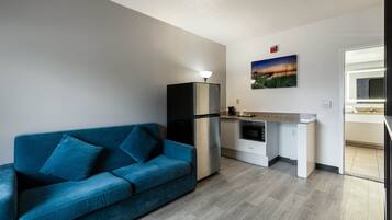 Um espaço compacto com cozinha compacta, um sofá azul e um quadro na parede.
