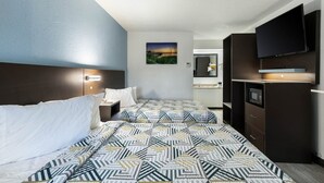 Une chambre d’hôtel avec un lit, une table de chevet, une télévision, un miroir et un tableau au mur.