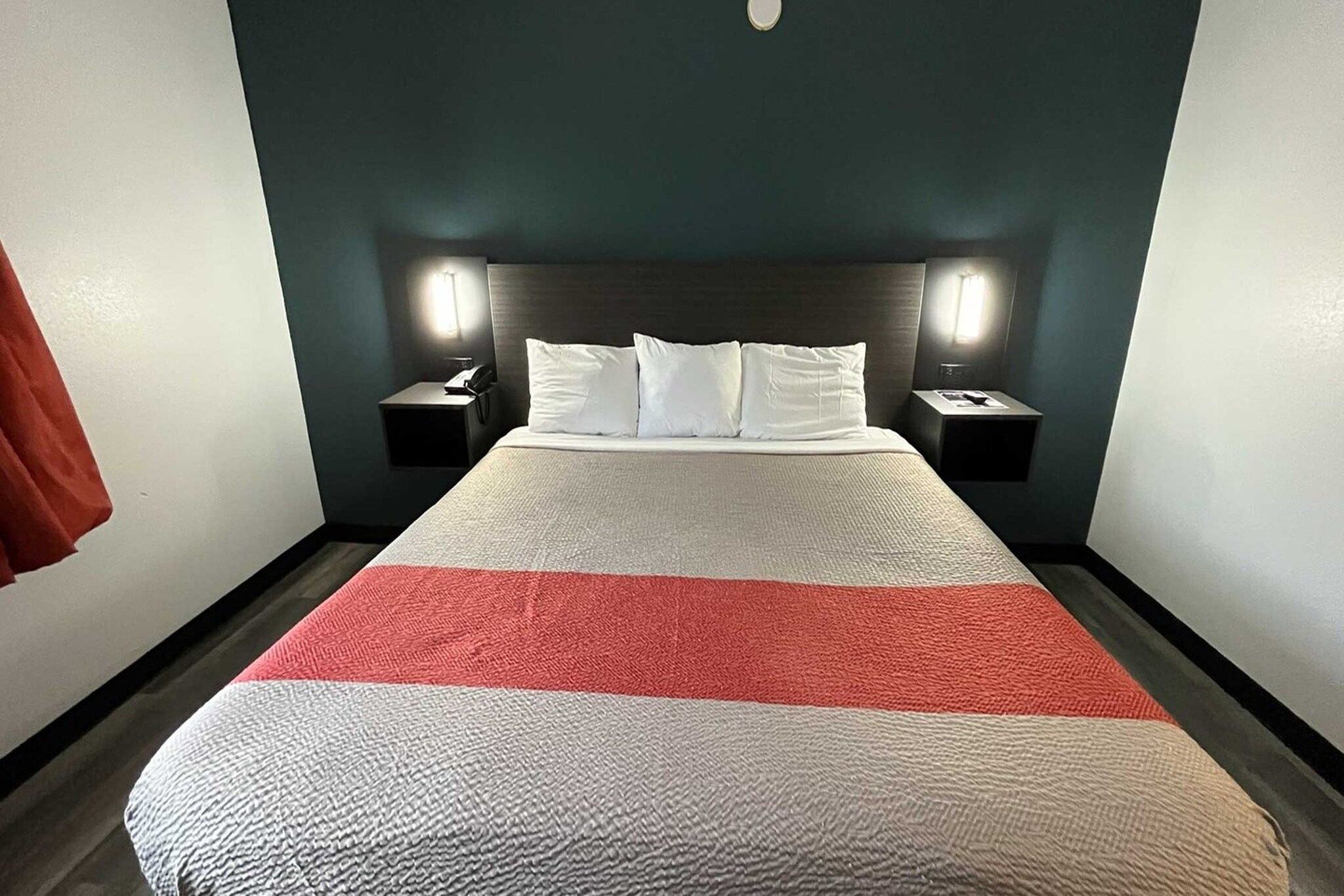 Une chambre d’hôtel avec un lit, deux tables de chevet et une petite table d’appoint.