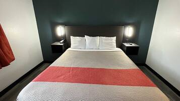 Une chambre d’hôtel avec un lit, deux tables de chevet et une petite table d’appoint.