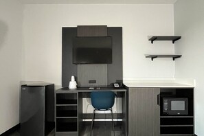 A compact office space with a desk, chair, mounted television, and a microwave. - 1 King Bed | Non-Smoking, Micfridge (Urbana, IL)