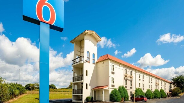 Un edificio con un letrero llamativo que dice 'Motel 6' y una estructura en forma de torre con balcones.