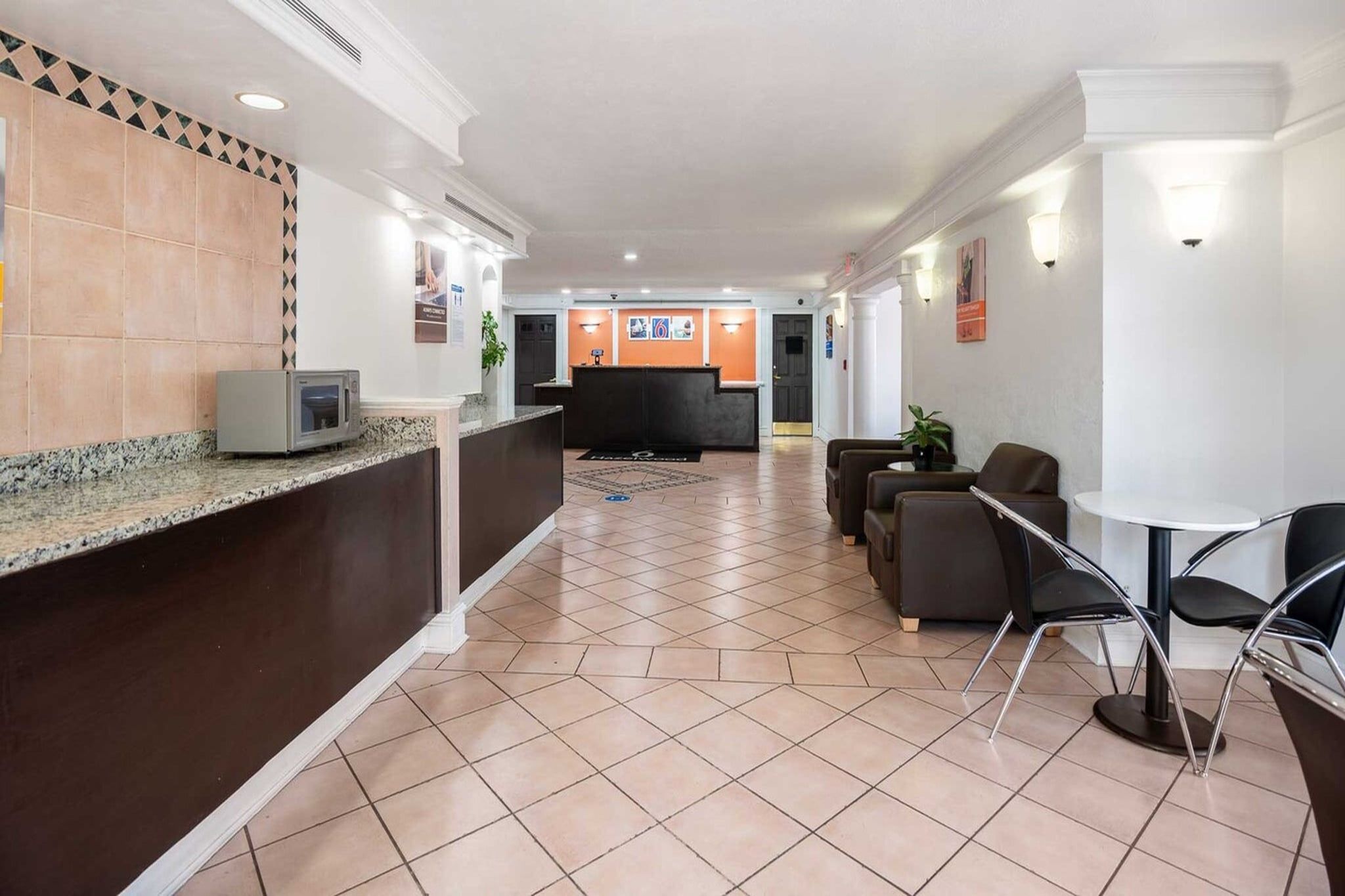 Un hall d’hôtel comprenant un comptoir d’accueil, un espace détente avec des sièges et un bureau de réception.