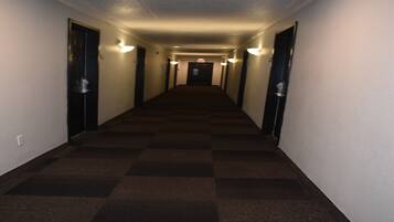 Ein Hotelgang mit Teppichböden, Türen auf beiden Seiten und Wandleuchten.