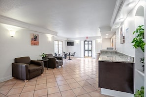 A spacious lobby with a reception desk, seating area, and a television screen. - 1 King Bed | Non-Smoking, Micfridge (Hazelwood MO)