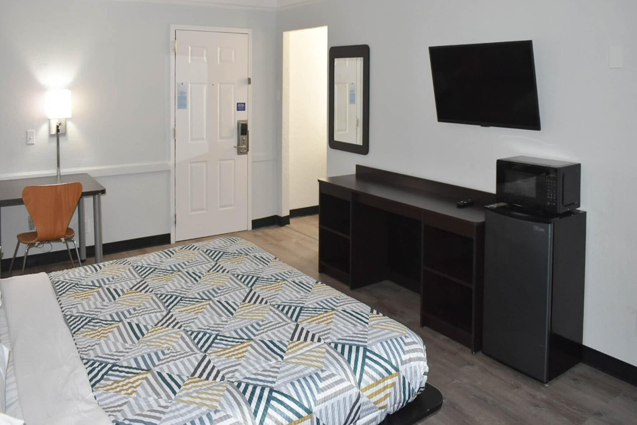 Une chambre d’hôtel équipée d’un lit, d’un bureau, d’une chaise, d’une télévision et d’un four à micro-ondes.