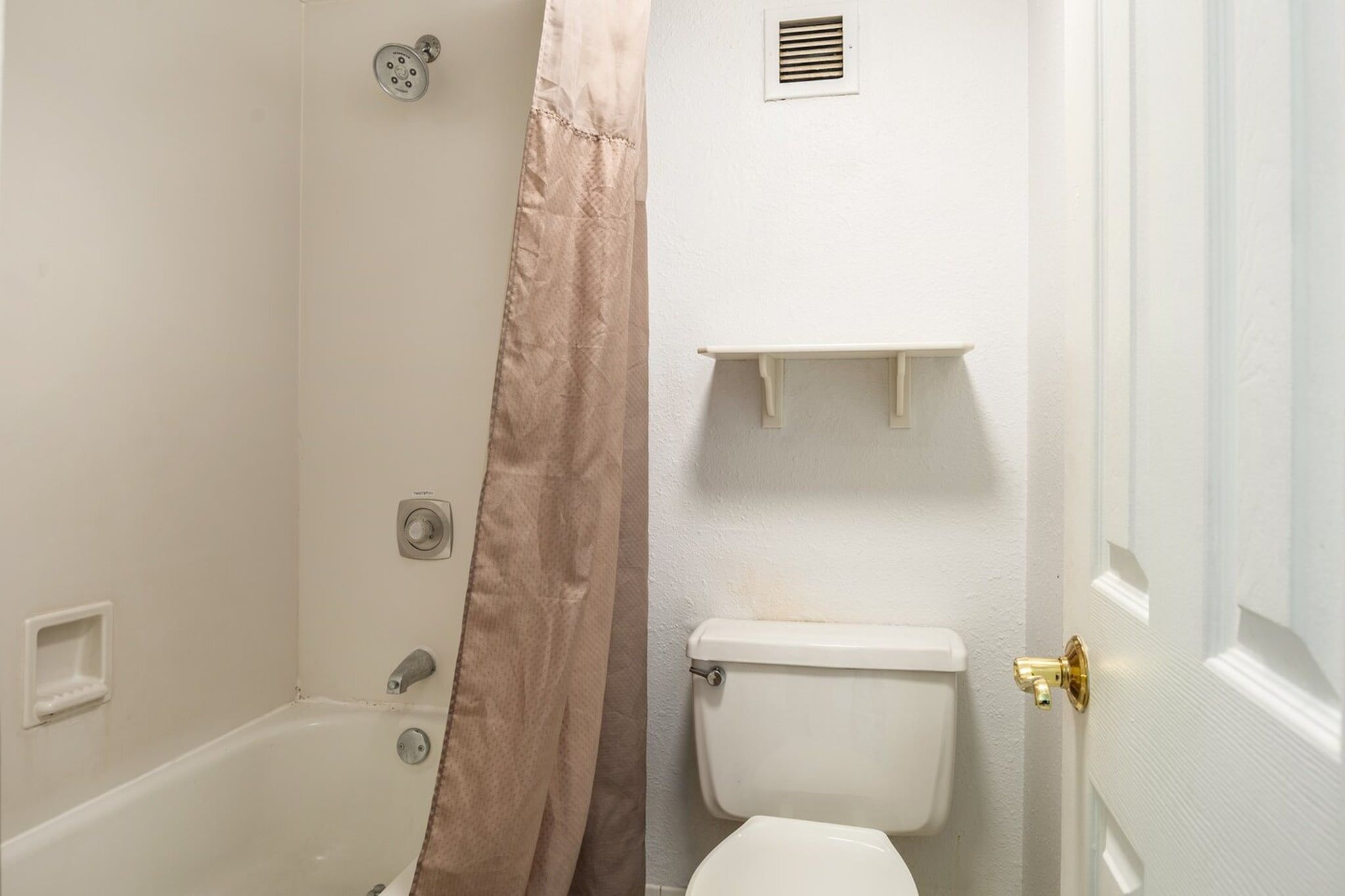 Un bagno con doccia, WC e ripiano sopra il water.