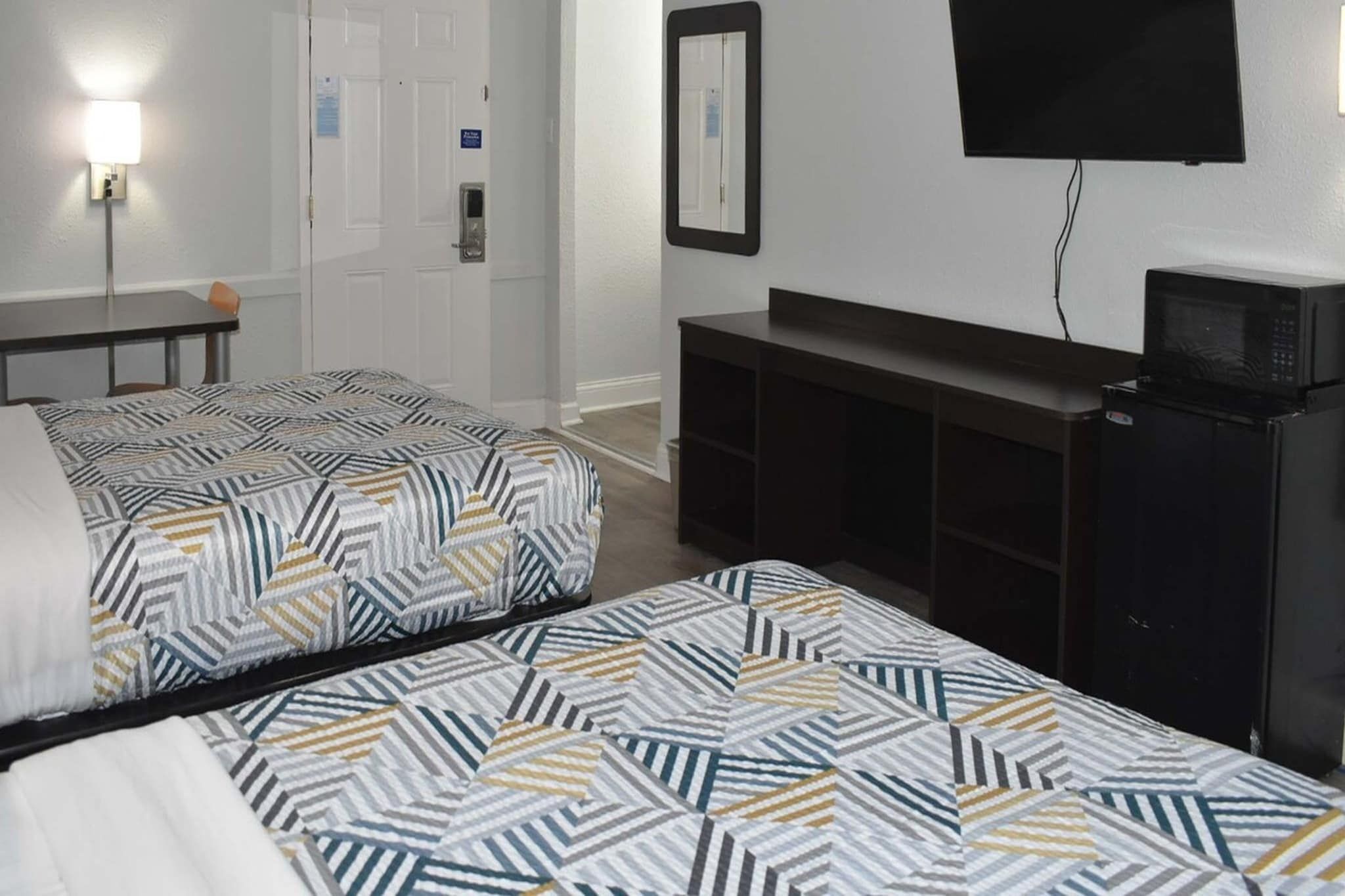 Une chambre d’hôtel avec deux lits, une télévision, un four à micro-ondes et un bureau.