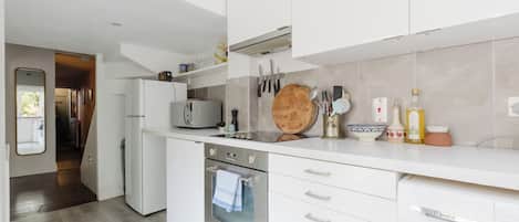 A modern kitchen with white cabinetry, a built-in oven, and a microwave.