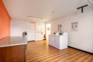 Une cuisine propre et bien éclairée, équipée d’un plan de travail, d’un lave-linge et d’un réfrigérateur.