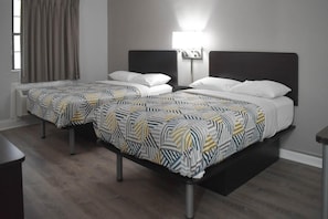Ein Hotelzimmer mit zwei Betten, jeweils mit einem gemusterten Überwurf und weißen Kissen.