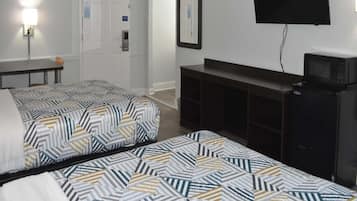 A hotel room with two beds, a TV, a microwave, and a desk.