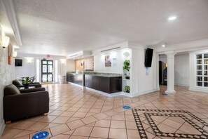 Eine Hotelhalle mit einer Rezeption, einer Sitzecke und einem gefliesten Boden.