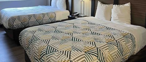 A hotel room with two beds, each with patterned bedding, a bedside lamp, and a telephone on the nightstand.
