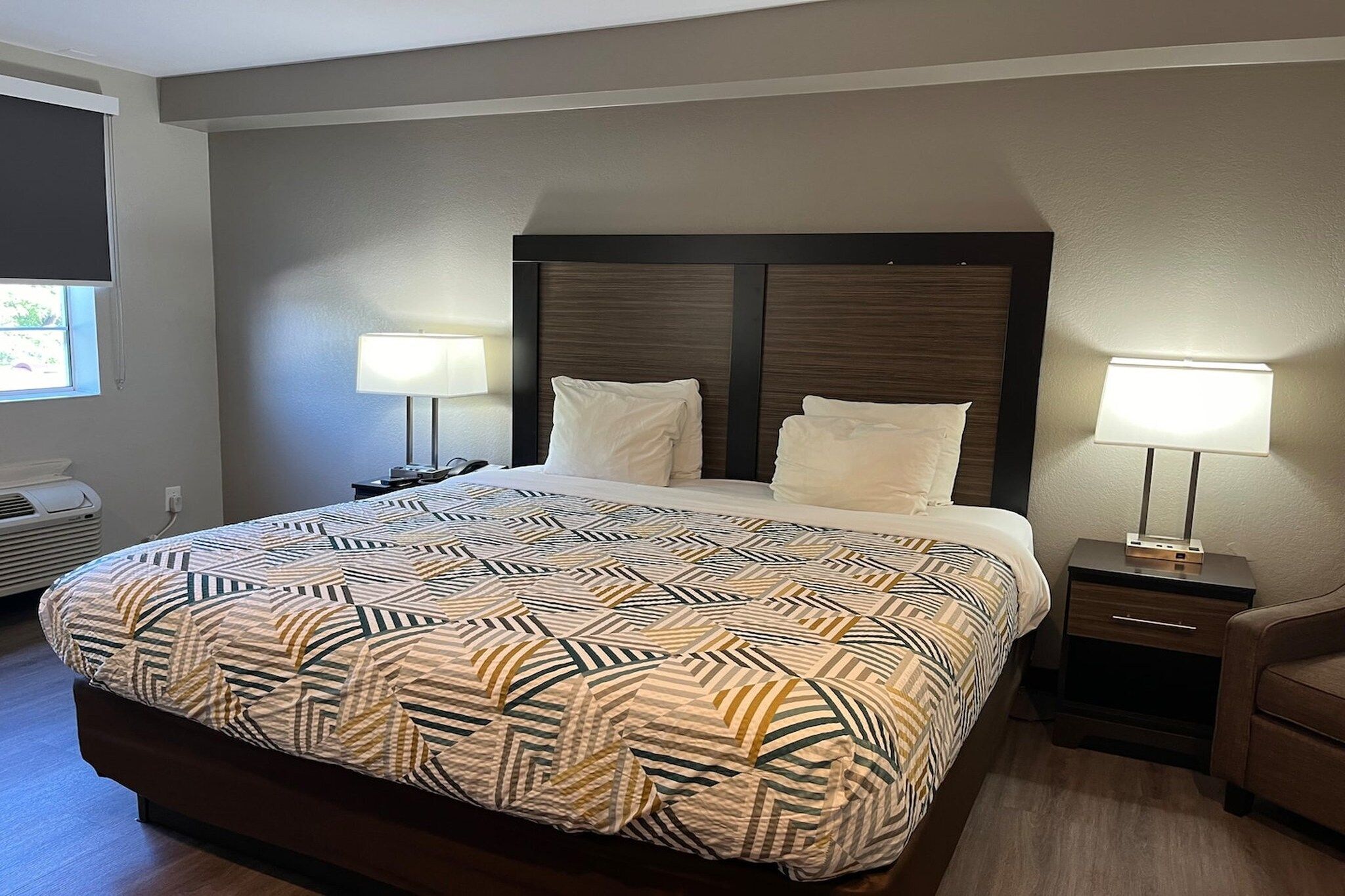 Une chambre d’hôtel avec un grand lit, deux tables de chevet, un téléviseur fixé au mur et une fenêtre.