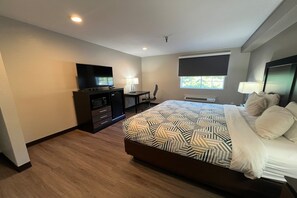 Ein Hotelzimmer mit Bett, Schreibtisch, Stuhl, Fernseher und Fenster.