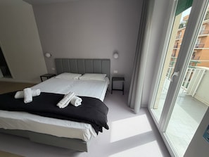 A hotel room with a bed, two bedside tables, a window with a view of the outside, and a curtain. - Luciano King's Guest House (Rome)