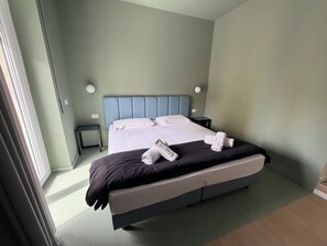 A neatly made bed with white linens and towels, a blue headboard, and a small bedside table with a lamp. - Luciano King's Guest House (Rome)
