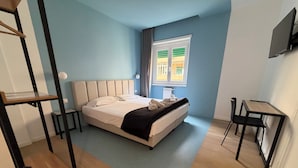 A bedroom with a bed, bedside tables, a desk, and a window with curtains. - Luciano King's Guest House (Roma)