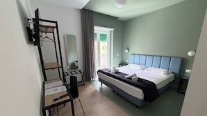 A hotel room with a bed, a desk, a chair, a mirror, and a window with curtains. - Luciano King's Guest House (Roma)