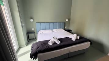 A hotel room with a bed, a nightstand, and a wall-mounted lamp.