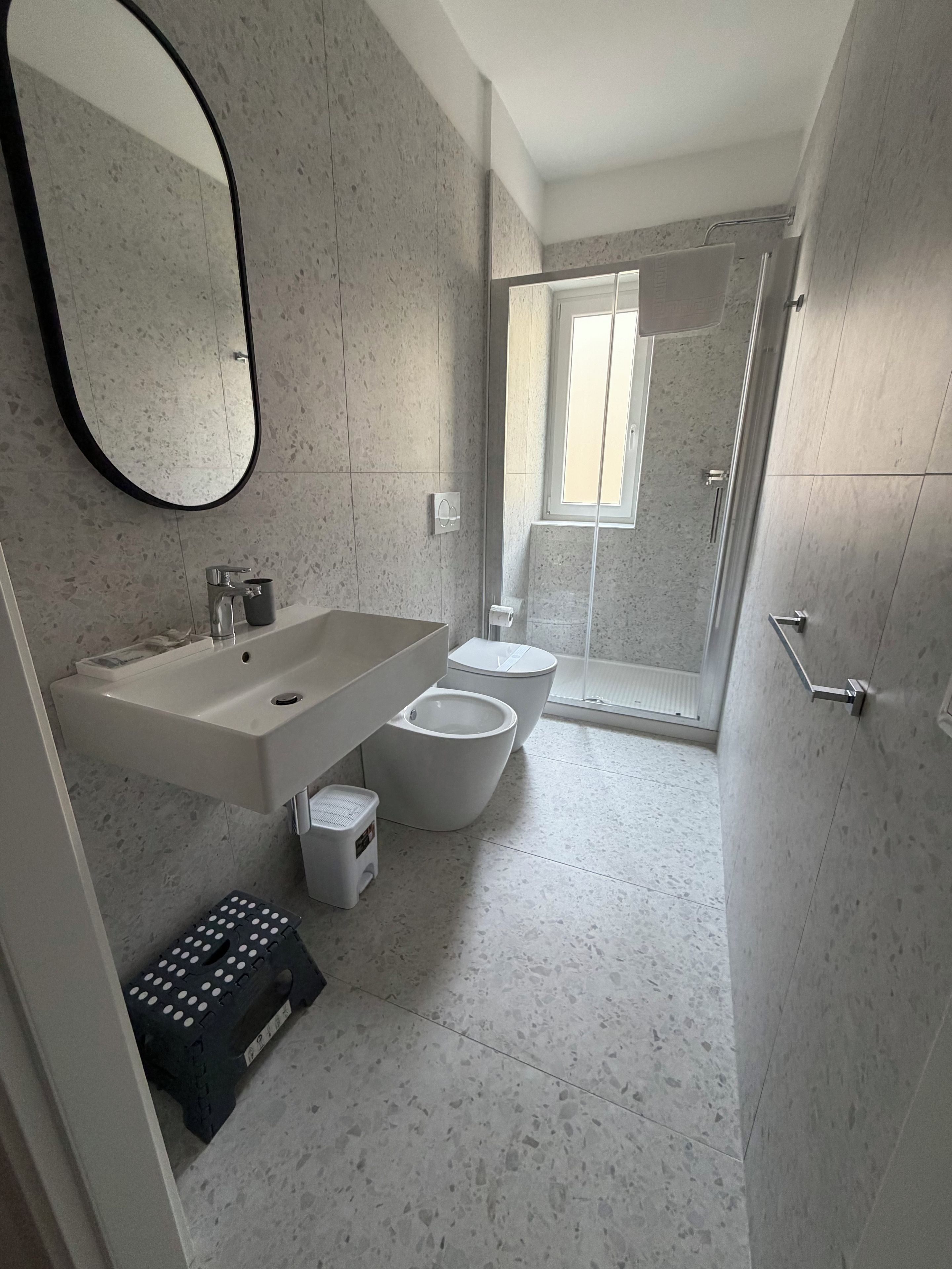 A modern bathroom with a freestanding sink, a toilet, and a shower enclosure.