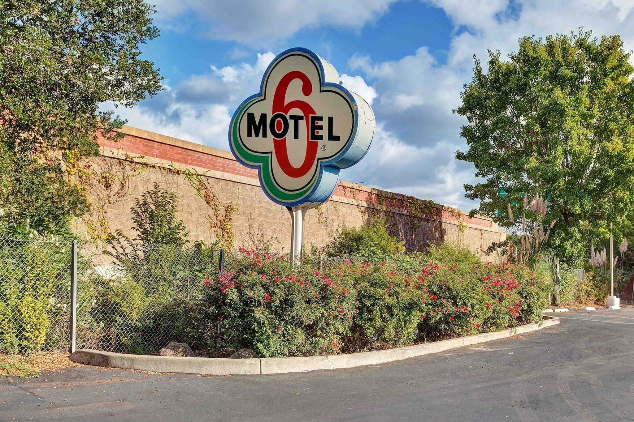 A motel sign with a circular logo and the word 'MOTEL' on a clear day.