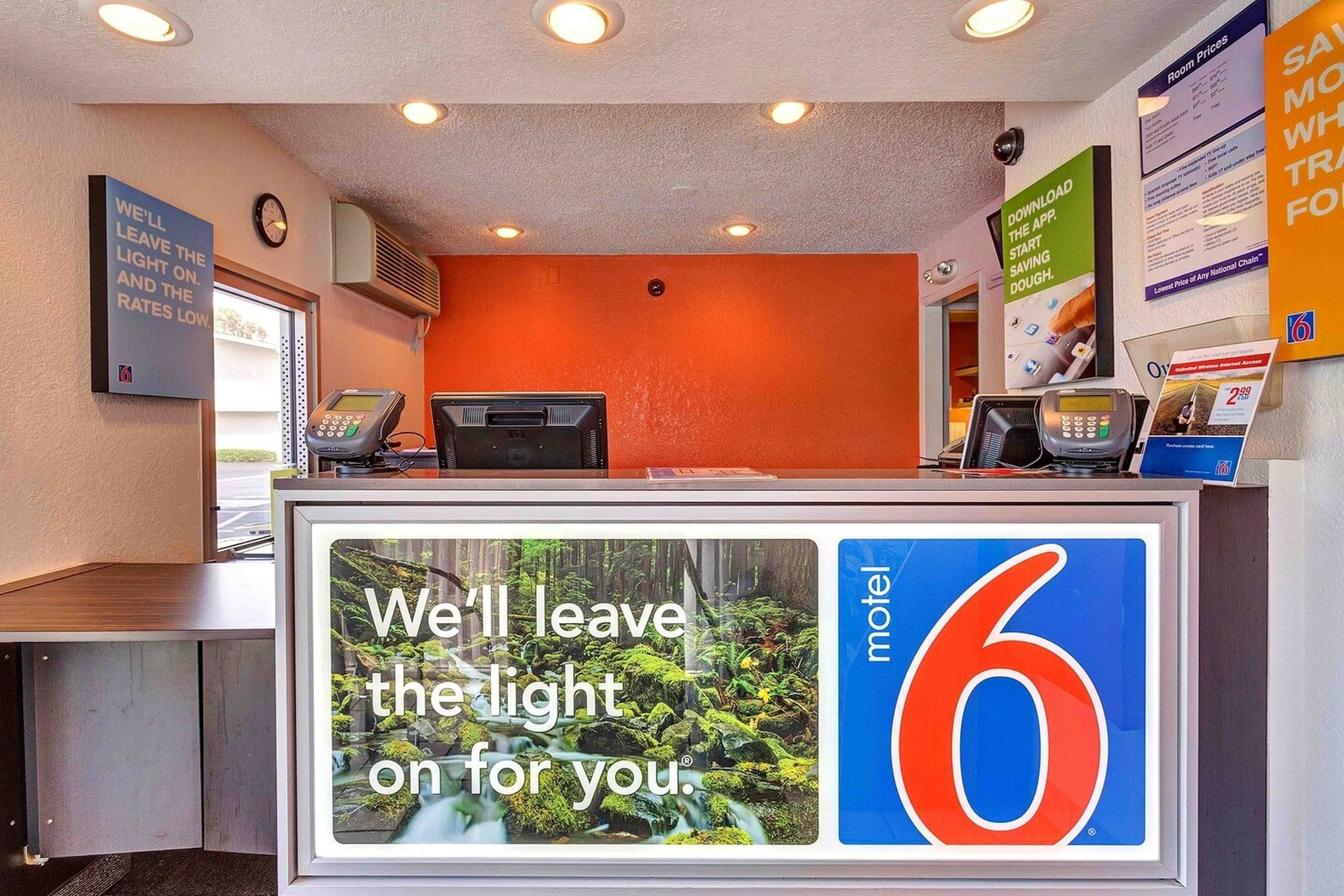 A motel reception desk with a large sign stating 'We'll leave the light on for you.'