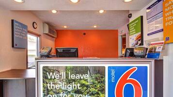 A motel reception desk with a large sign stating 'We'll leave the light on for you.'