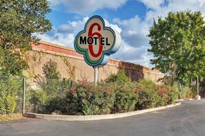 A motel sign with a circular logo and the word 'MOTEL' on a clear day.