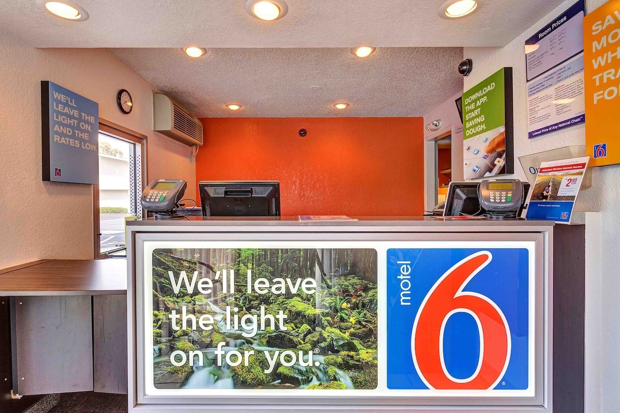 A motel reception desk with a large digital display advertising the motel's services.