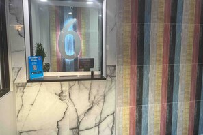 Un área de recepción con pared de mármol y una pared con rayas de colores.