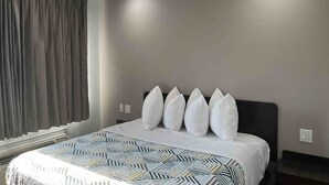 Quarto de hotel com cama, janela com cortinas e interruptor de luz na parede.