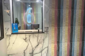 Un área de recepción con pared de mármol y una pared con rayas de colores.