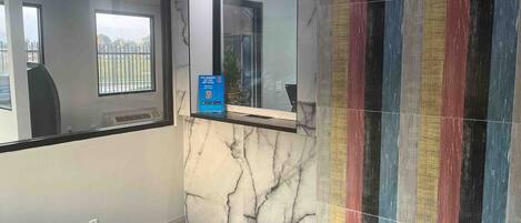 A bathroom with a marble wall, a mirror, and a colorful striped tile accent.