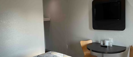 Habitación de hotel con cama, una mesita, dos sillas y un televisor montado en la pared.