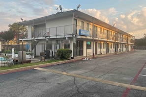 Un edificio de dos pisos con un letrero que dice 'Bienvenido', un letrero que indica 'Recepción' y un letrero de 'Límite de velocidad 0'.