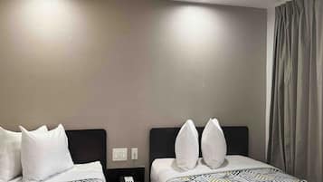 A hotel room with two beds, each with patterned bedding and white pillows. There is a nightstand with a phone between the beds.