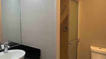 Ett badrum med ett vitt handfat, en dusch med glasdörr och en toalett.