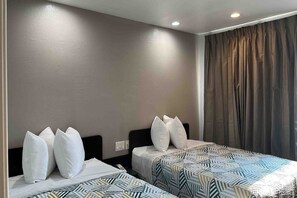 Una habitació d'hotel amb dos llits, cada un amb un estriat i coixins blancs.