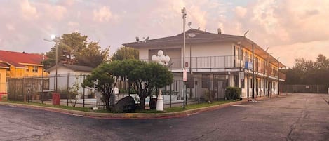 A two-story building with a gated entrance, satellite dishes, and a parking lot.