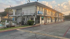 Um edifício de dois andares com uma placa de 'Welcome', uma placa de 'Lobby' e uma placa de 'Speed Limit 0'.