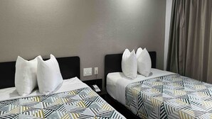 Quarto de hotel com duas camas, cada uma com roupa de cama estampada e travesseiros brancos.
