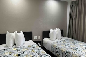 Habitación de hotel con dos camas, cada una con ropa de cama estampada y almohadas blancas.
