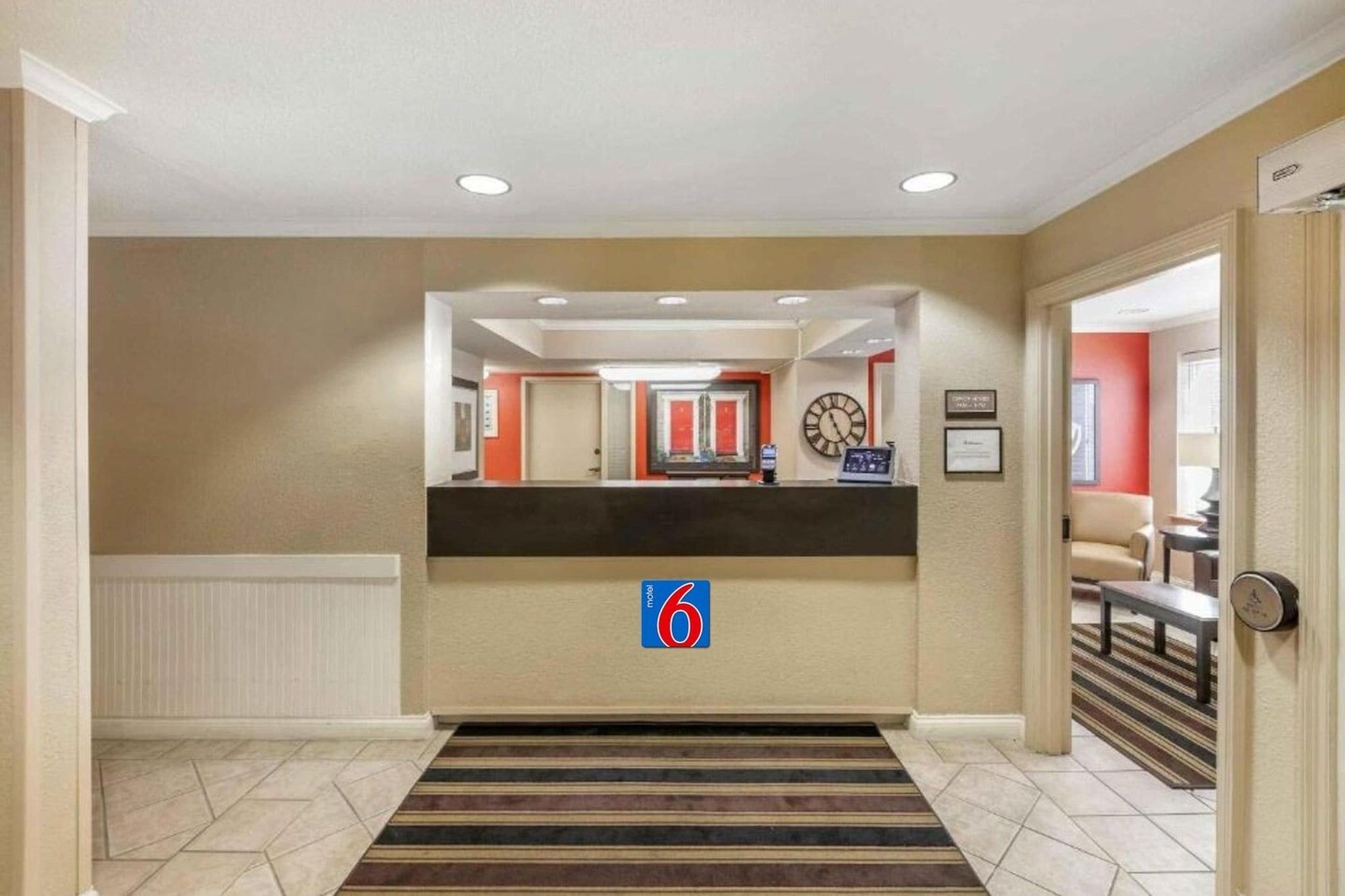 A hotel reception area with a reception desk, a clock, and a sign indicating room number 6.