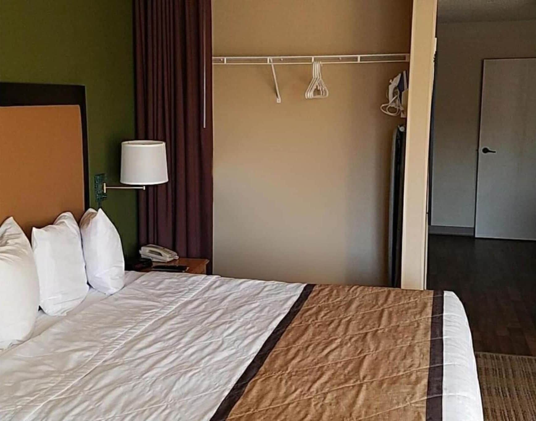 Una habitación de hotel con cama, lámpara, teléfono y puerta.
