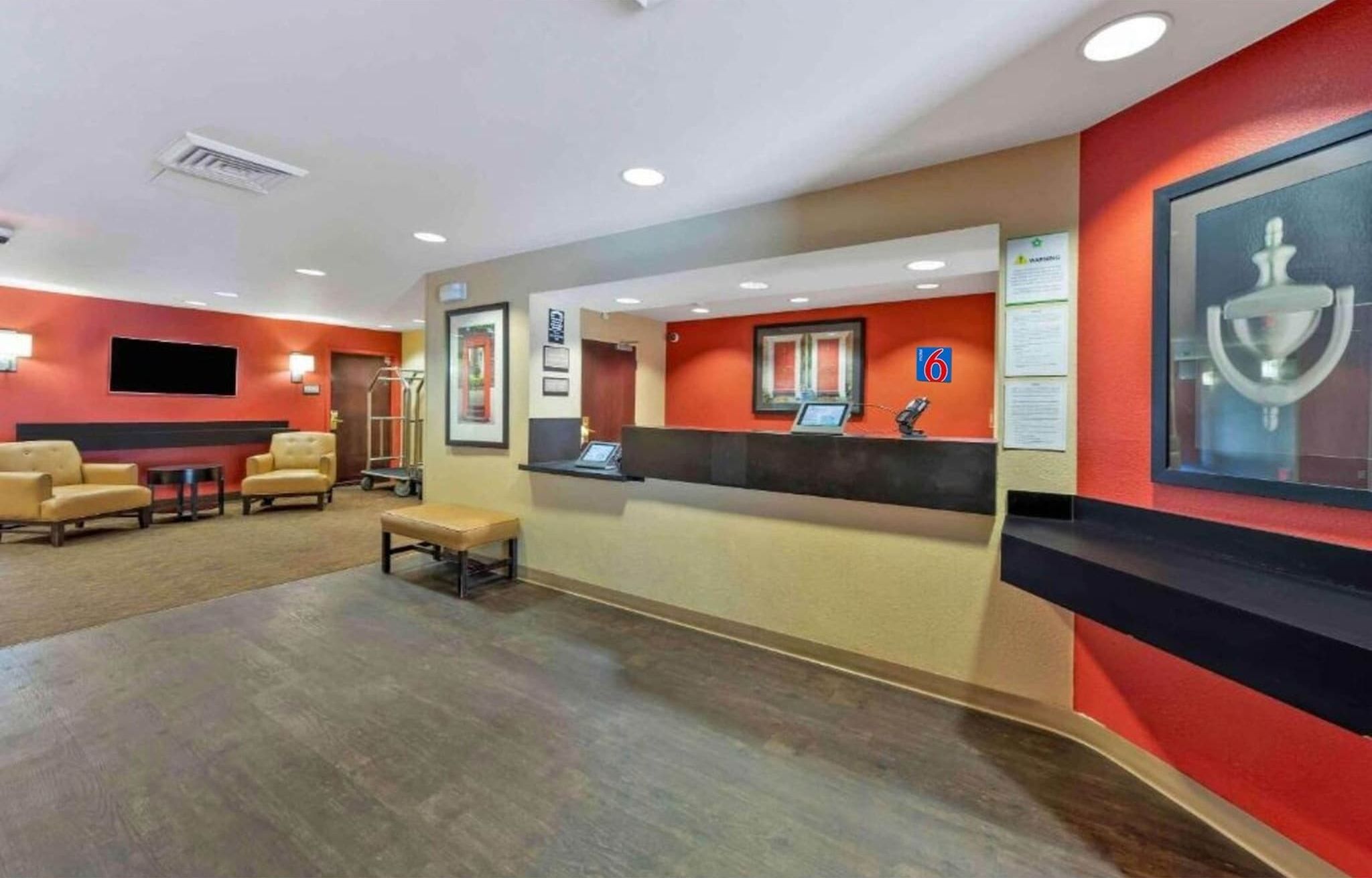 A hotel reception area with a reception desk, seating area, and a television screen.
