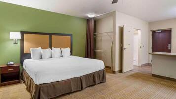 Une chambre d’hôtel comprenant un lit, une table de chevet, une lampe, une armoire et une porte donnant sur une autre pièce.