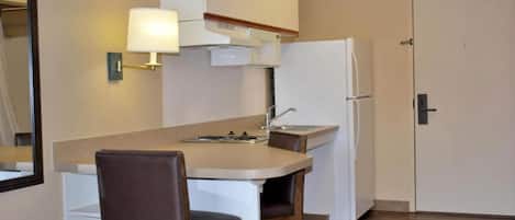 A compact kitchen with a dining area, a refrigerator, a sink, and a cabinet.